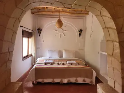 a bedroom with a large bed in a stone wall at Kasbah Chems in Kalaat MGouna