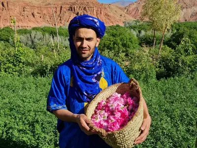 a man holding a basket of pink flowers at Kasbah Chems in Kalaat MGouna