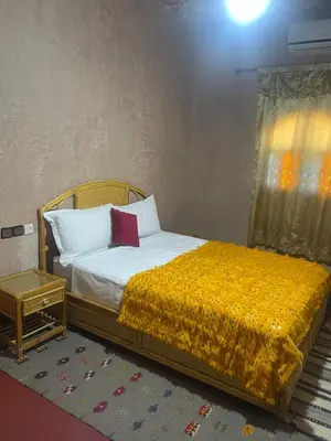a bedroom with a bed with a yellow blanket at Dar nadia bendriss in Ouarzazate