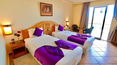 two beds in a hotel room with purple sheets at Hotel Menzeh Dalia in Meknès