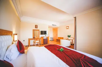 a bedroom with a bed and a living room at Hotel Menzeh Dalia in Meknès