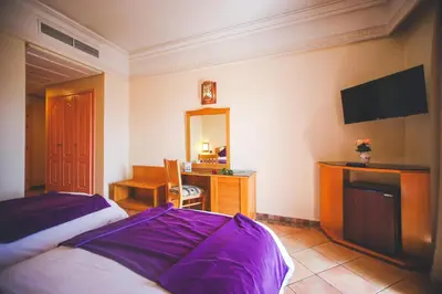 a bedroom with a bed and a desk and a mirror at Hotel Menzeh Dalia in Meknès