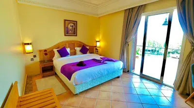 a bedroom with a large bed with purple sheets at Hotel Menzeh Dalia in Meknès