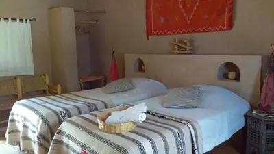 a bedroom with two beds and a basket of towels at Dar Lorkam in Skoura