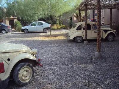 two old cars parked in a gravel parking lot at Dar Lorkam in Skoura