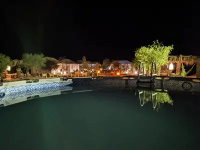 a pool of water at night with a bridge at Sahara Majestic Luxury Camp in Merzouga