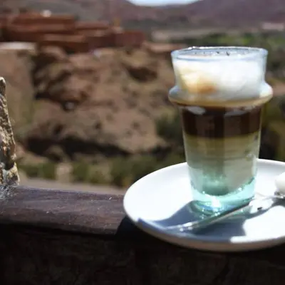 a cup of coffee on a plate with a spoon at Dar Isselday in Tisselday