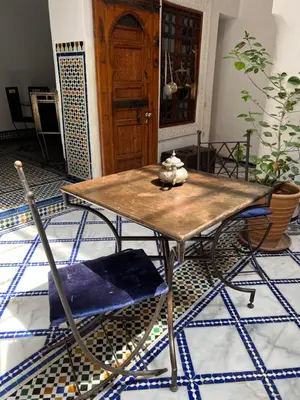 a wooden table and a chair in a room at Dar Faracha Fes in Fès