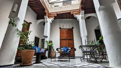an indoor courtyard with chairs and a wooden door at Dar Faracha Fes in Fès