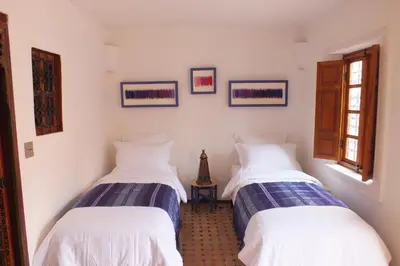 two beds in a room with white walls at Dar Faracha Fes in Fès