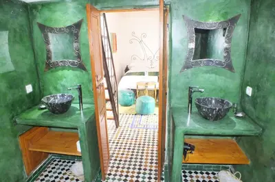 a green bathroom with two sinks and a mirror at Dar Faracha Fes in Fès