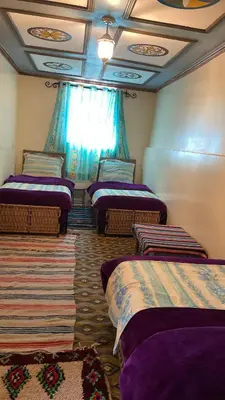 a room with four beds in a room with a window at Kasbah Ait Bouguemez in Agouti