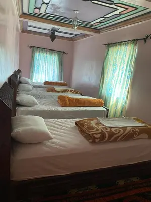a group of four beds in a room with windows at Kasbah Ait Bouguemez in Agouti