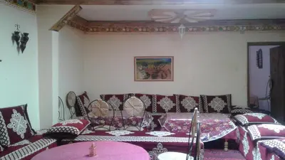 a room with chairs and a table and a ceiling fan at Kasbah Ait Bouguemez in Agouti