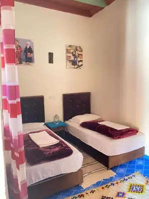 two twin beds in a room with a rug at Kasbah Ait Bouguemez in Agouti