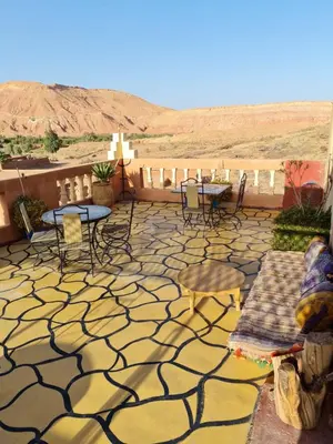 a patio with tables and chairs and a view of the desert at Riad Tigmi du Soleil in Aït Ben Haddou