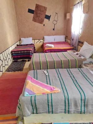 a group of three beds in a room at Riad Tigmi du Soleil in Aït Ben Haddou