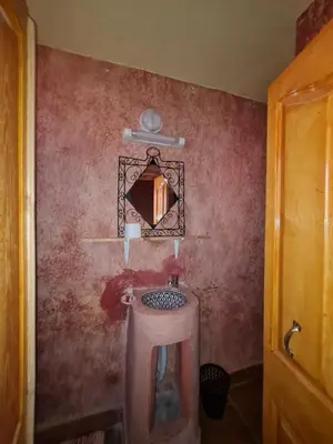 a bathroom with a sink and a red wall at Riad Tigmi du Soleil in Aït Ben Haddou