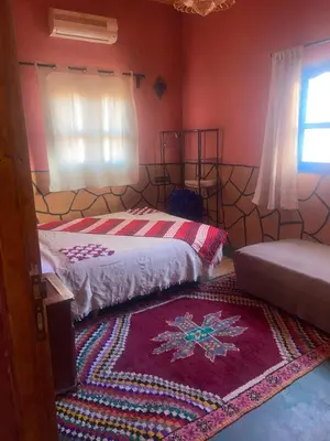a bedroom with a bed and a rug on the floor at Riad Tigmi du Soleil in Aït Ben Haddou
