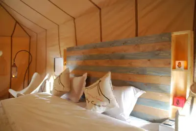 a bedroom with a large bed with a wooden headboard at Boho Glamping in Merzouga