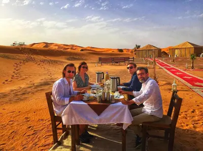 a group of people sitting at a table in the desert at Boho Glamping in Merzouga