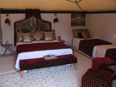 a bedroom with two beds and a table in it at Sahara Luxury Tents in Merzouga
