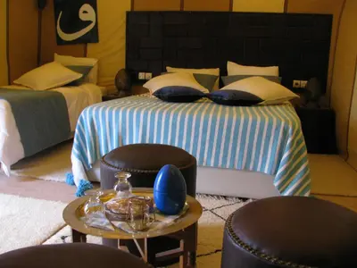 a bedroom with two beds and a table with chairs at Sahara Luxury Tents in Merzouga