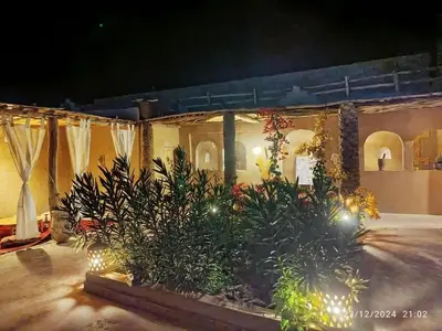 a patio with plants and lights in front of a building at Dar Nomads in Mhamid