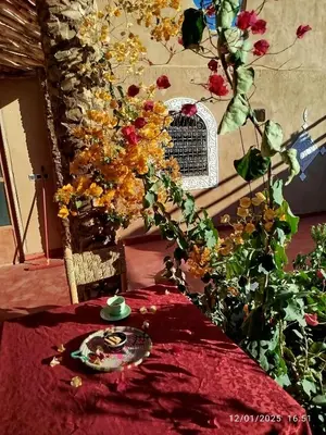 a table with a red table cloth and flowers on it at Dar Nomads in Mhamid