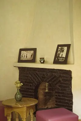 a room with a fireplace with a table and pictures at Auberge Ayam Atlas- pool 10mn away in Ourika