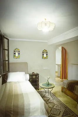 a bedroom with a bed and a table and a chandelier at Auberge Ayam Atlas- pool 10mn away in Ourika