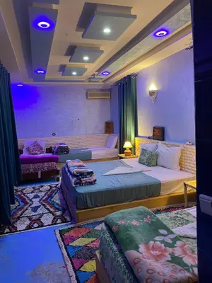 a hotel room with two beds and a couch at Hôtel familiale les grotte in Aït Ben Haddou