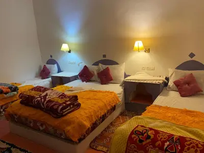 a hotel room with three beds in a room at Hôtel familiale les grotte in Aït Ben Haddou
