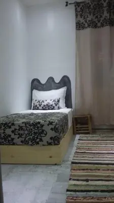 a bedroom with a black and white bed and a rug at Hôtel familiale les grotte in Aït Ben Haddou