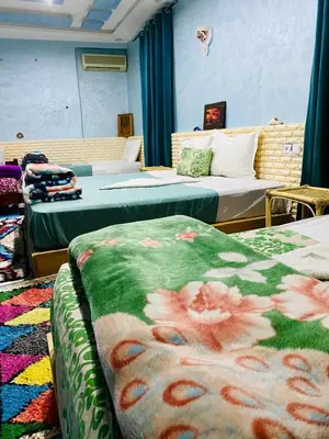 a bedroom with two beds and a bedvisor with flowers on it at Hôtel familiale les grotte in Aït Ben Haddou