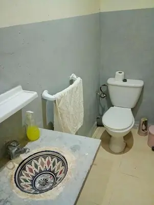 a bathroom with a white toilet and a sink at Hôtel familiale les grotte in Aït Ben Haddou