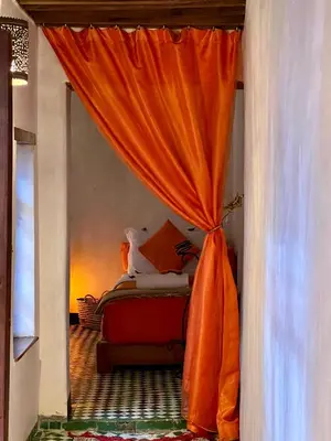 a bedroom with a bed with an orange curtain at Dar Attajalli in Fès