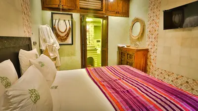 a bedroom with a large white bed and a bathroom at ferme by Ikalimo in Ourika