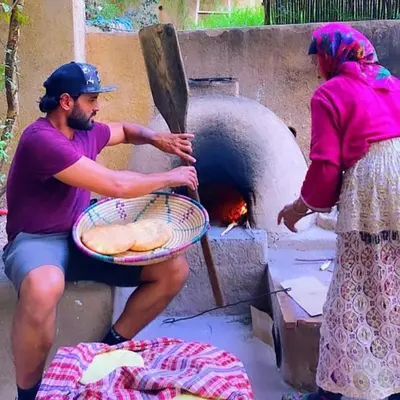 a man and a woman putting bread into an oven at ferme by Ikalimo in Ourika