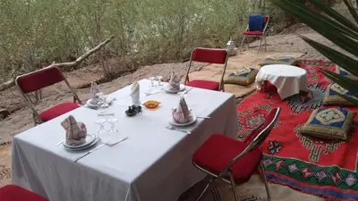 a table with red chairs and a white table with glasses at Auberge Restaurant TISSILI 