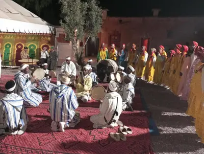 a group of people sitting on a rug in front of a stage at Auberge Restaurant TISSILI 