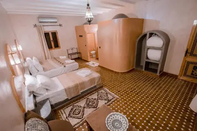 a large room with two beds and a fireplace at Hassilabiad Appart Hotel in Merzouga