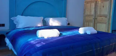 a blue bed with two towels on top of it at Hassilabiad Appart Hotel in Merzouga