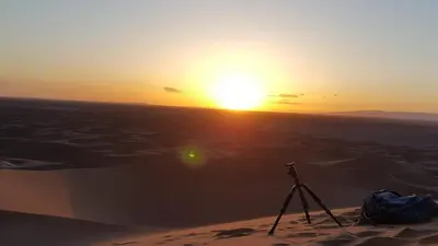 a camera in the desert with the sunset in the background at Erg Chigaga Camp Shooting Stars in Mhamid