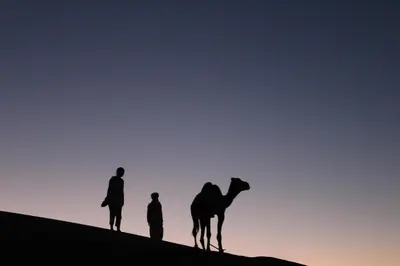 two people and a camel on top of a hill at Erg Chigaga Camp Shooting Stars in Mhamid