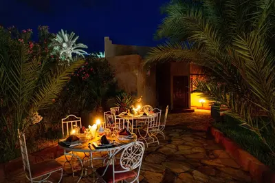 a table and chairs in a garden at night at Riad Zagora Palms in Zagora