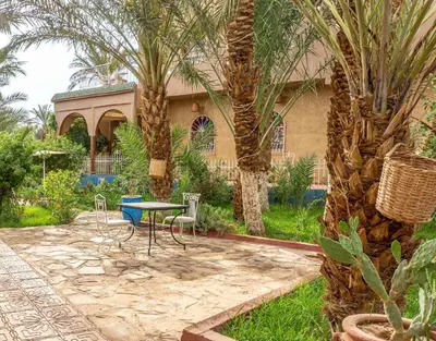 a patio with a table and chairs and palm trees at Riad Zagora Palms in Zagora