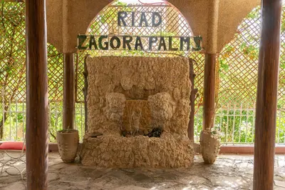 a large stone fireplace in a building with a gate at Riad Zagora Palms in Zagora