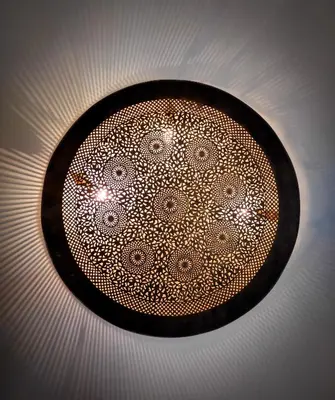 a black plate with a mandala design on a ceiling at Dar Naima in Fès
