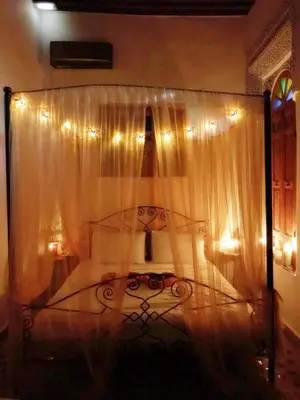 a bedroom with a bed with curtains and lights at Dar Naima in Fès